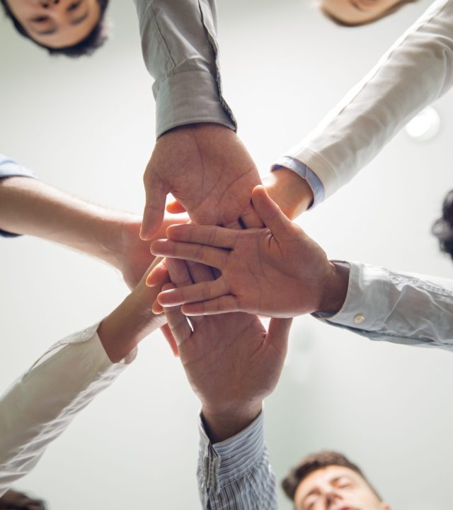 Below view of multiethnic business team stacking hands showing support, success and corporate spirit
